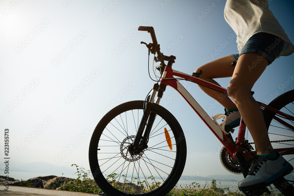 Fototapeta premium Hands free cycling woman riding mountain mike on sunrise seaside