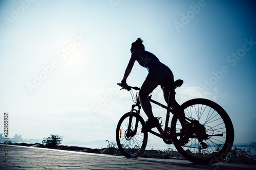 Cycling woman riding mountain mike on sunrise seaside