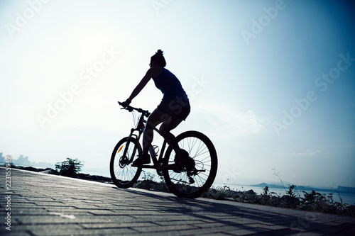 Cycling woman riding mountain mike on sunrise seaside