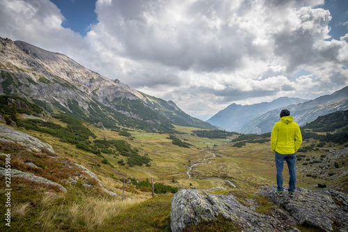 Junger selbstbwusster Mann in den Bergen, stehend, Blick in die Ferne, Abenteuer