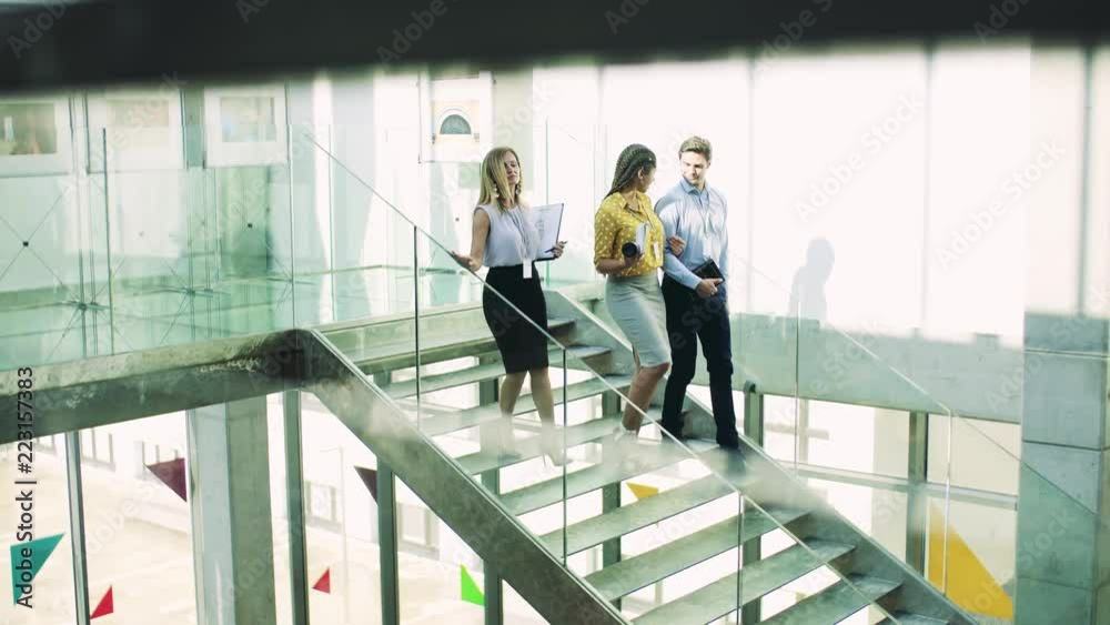 Businesspeople walking down the stairs in the modern building, talking. Businesspeople walking down the stairs in the modern building, talking.