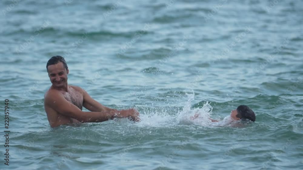 Father and son playing in the sea Jumping into the water Slow motion video Father and son playing in the sea Jumping into the water Slow motion video