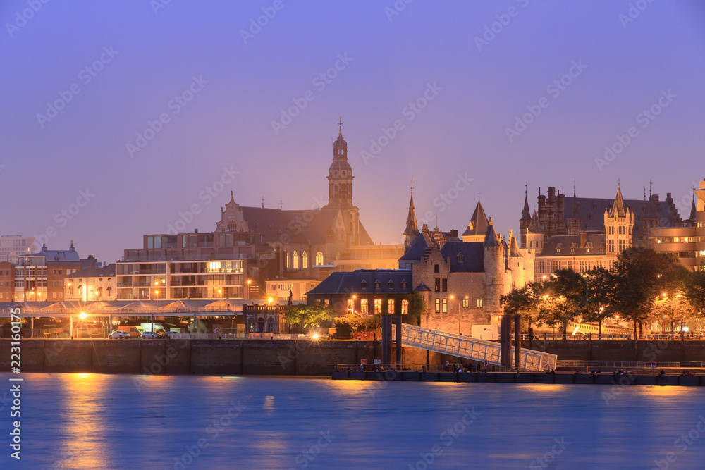 Beautiful cityscape of the skyline of Antwerp, Belgium, during the blue hour seen from the shore of the river Scheldt, with castle Het Steen and St. Paul's Church