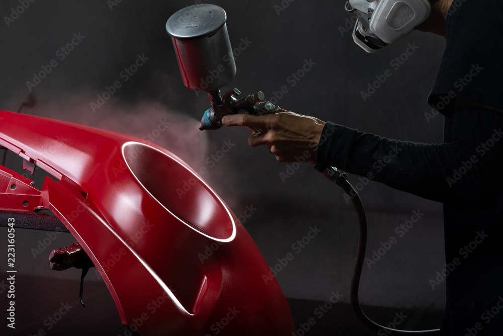 Fototapeta premium Seria automatycznych napraw nadwozia: czerwony zderzak malowany w kabinie lakierniczej