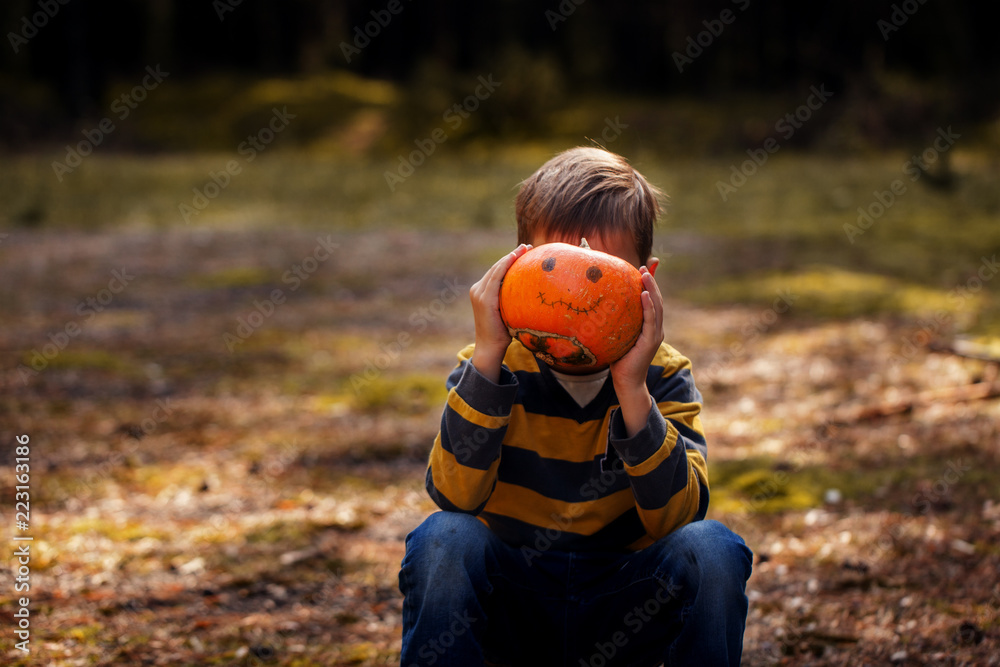 Funny boy with pumpkin on Halloween . The child holding pumpkin for holiday Halloween in outdoor Funny boy with pumpkin on Halloween . The child holding pumpkin for holiday Halloween in outdoor