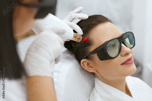 Cosmetology. Woman At Hair Growth Laser Stimulation Treatment