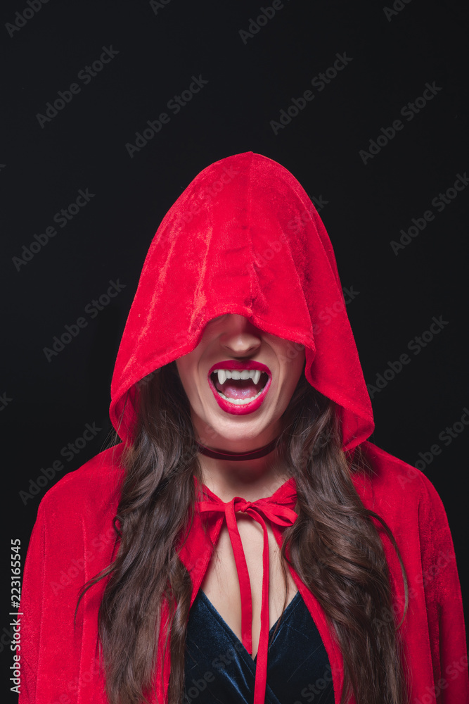 vampire woman in red cloak showing her fangs isolated on black vampire woman in red cloak showing her fangs isolated on black