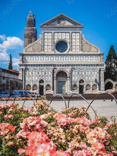 Beautiful small Basilica in Florence, surrounded by flower beds with pink flowers