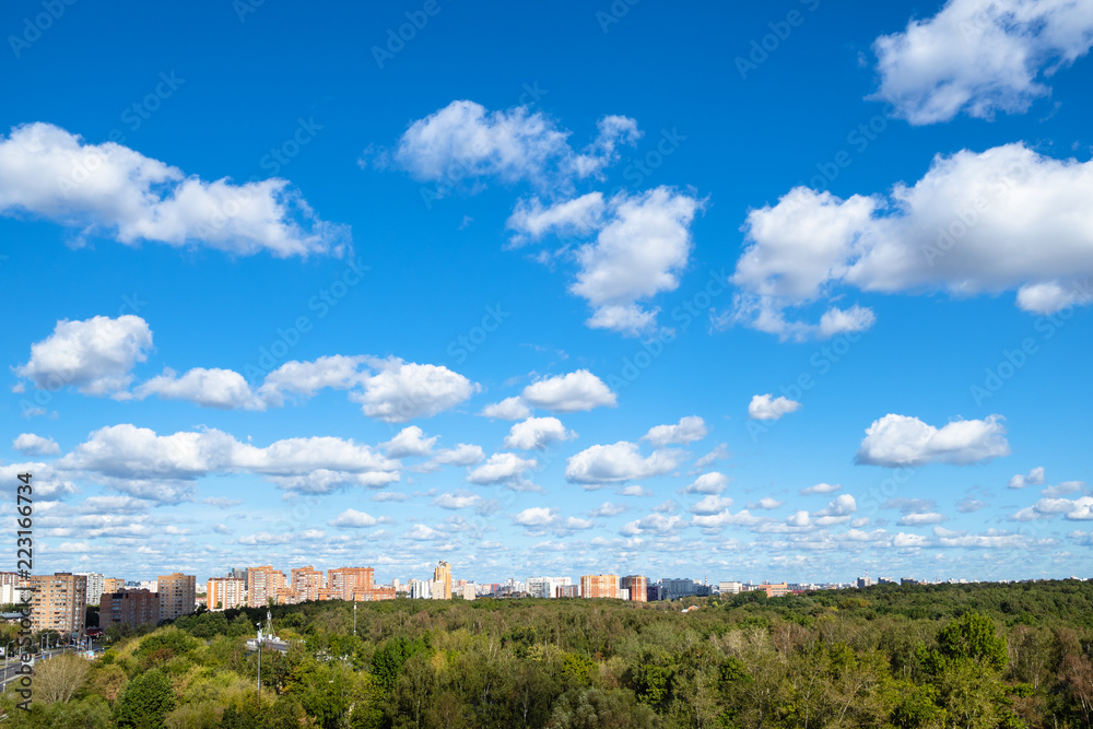 blue sky with many white clouds over park and city