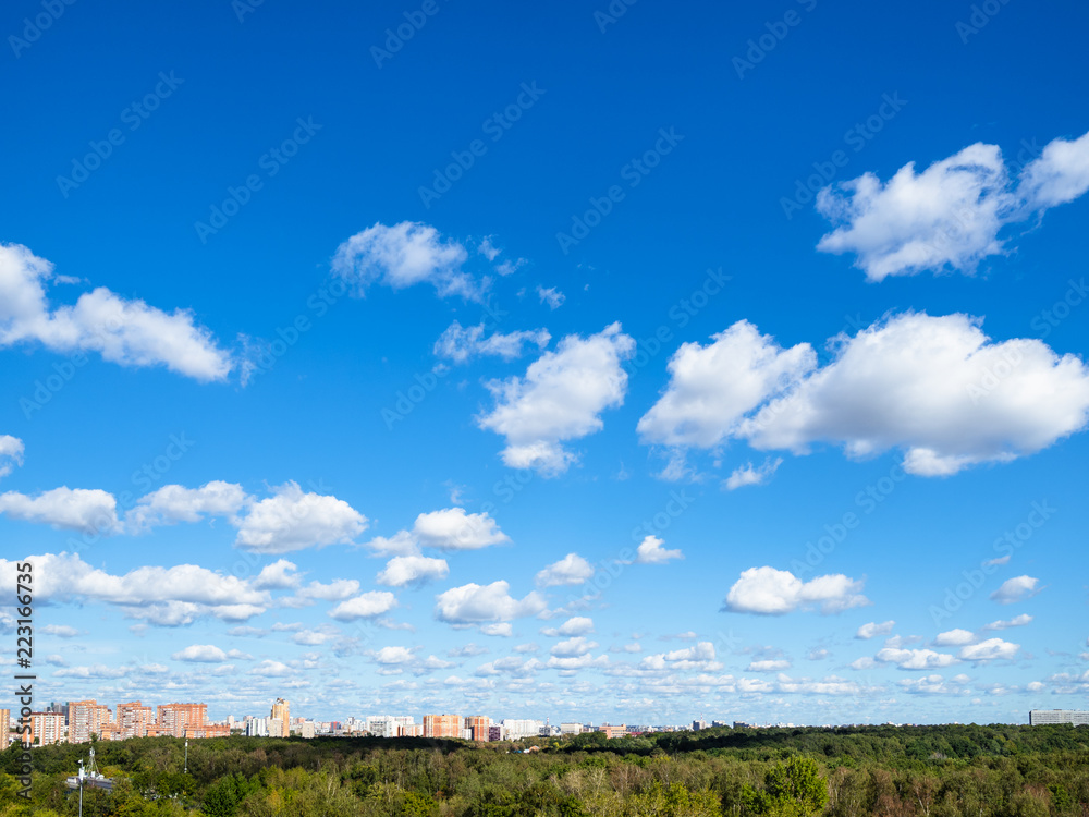 blue sky with many white clouds over wood and city blue sky with many white clouds over wood and city