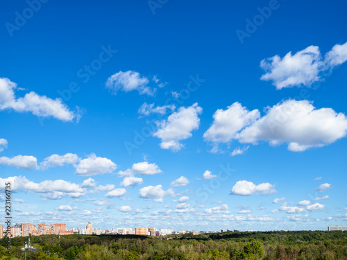 Canvas Print blue sky with many white clouds over wood and city
