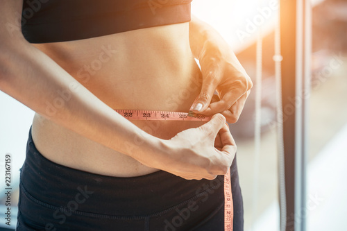 Photos A young woman wearing a workout in the fitness center are using waist measurement cables herself