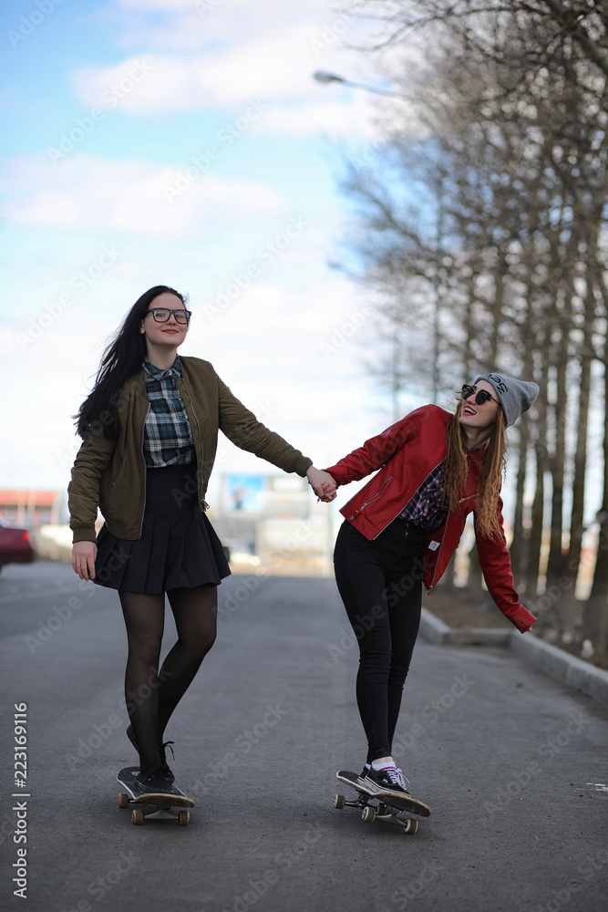 Obraz premium A young hipster girl is riding a skateboard. Girls girlfriends f