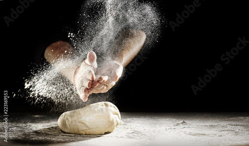 Foto Chef clapping his hands to dust dough with flour