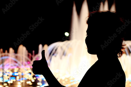 Fine girl on the street show Like for social network. Yonge woman on pastel background with jet fountain. Black silhouette, text space.