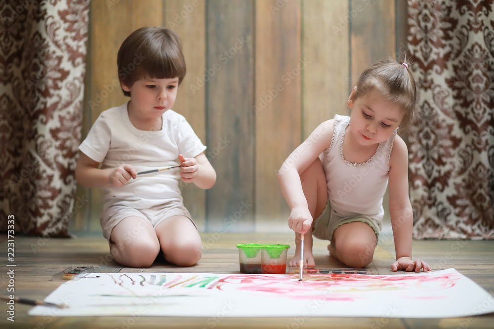 Little children paint on a large sheet of paper Little children paint on a large sheet of paper