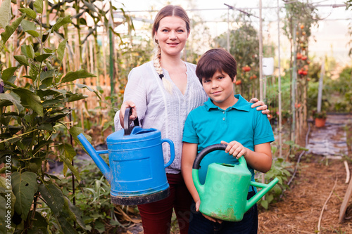 Little boy with mother  holding colorful watering  pots near seedlings