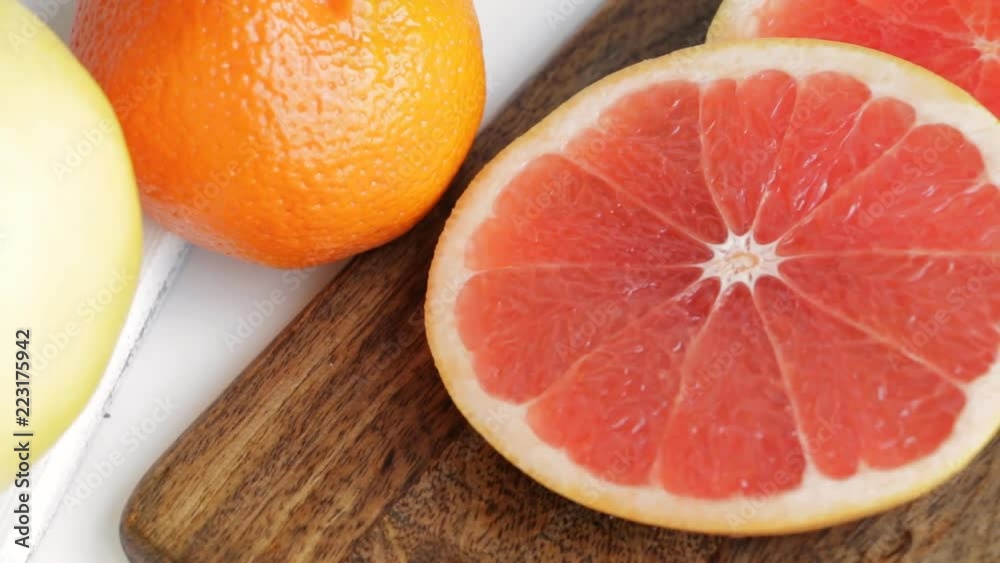 Fresh ripe citrus fruits - lemons, grapefruits, tangerines, mandarins - on white table. Selective focus. Camera slow pan. Closeup.