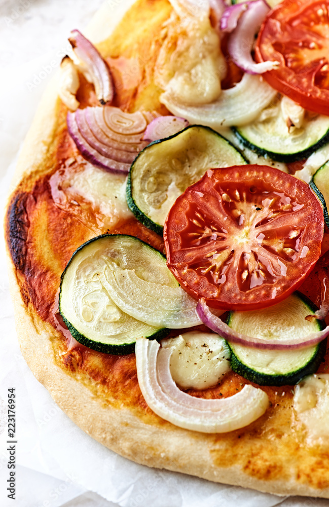 Home made vegetable pizza with zucchini, tomatoes, red onion and mozzarella.  Close-up
