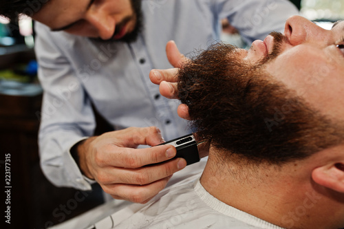 Handsome bearded man at the barbershop, barber at work.