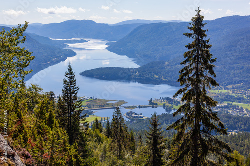 Aerial view on the vastness Norwegian landscape with small city Seljord on the shore of picturesque fjord with steep slopes covered with coniferous forest