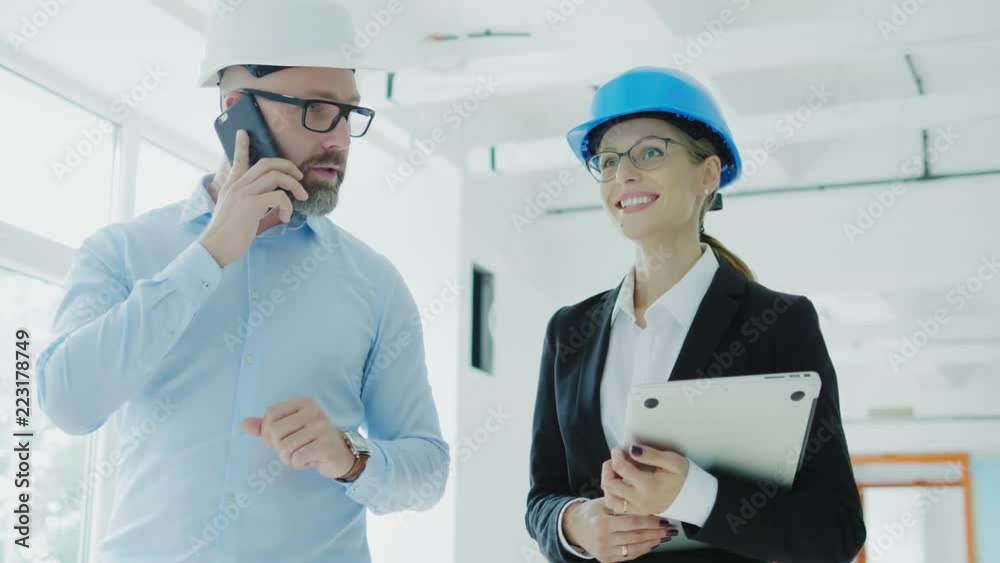 Engineers in hardhats have conversation in a factory Engineers in hardhats have conversation in a factory