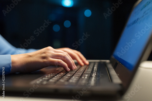 business, education and technology concept - close up of female hands with laptop typing at night
