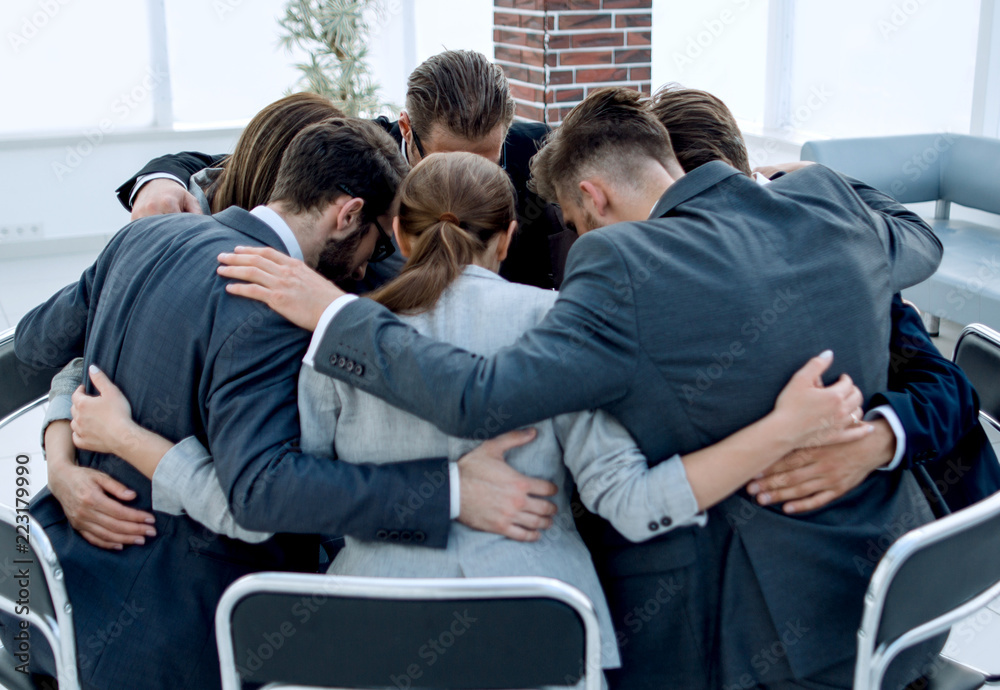 business team sits in a circle and hugs each other business team sits in a circle and hugs each other