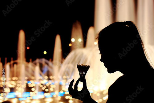 Silhouette of girl with badminton shuttlecock in hand.