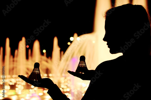 Silhouette of girl with badminton shuttlecock in hand.