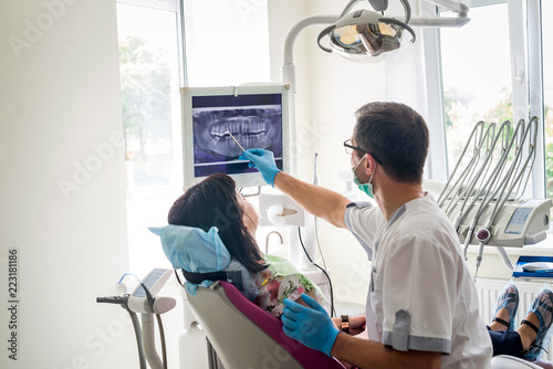 Doctor dentist showing patient's teeth on X-ray photo