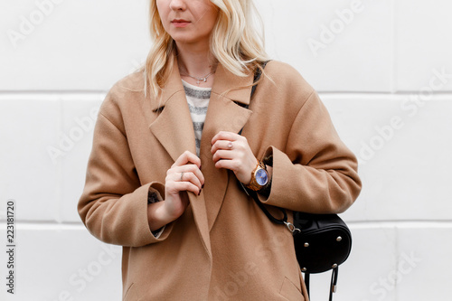 Wallpaper Mural Beautiful young stylish blonde woman wearing beige coat and black backpack posing near white street wall. Trendy casual outfit. Street fashion. Details of everyday look. Torontodigital.ca