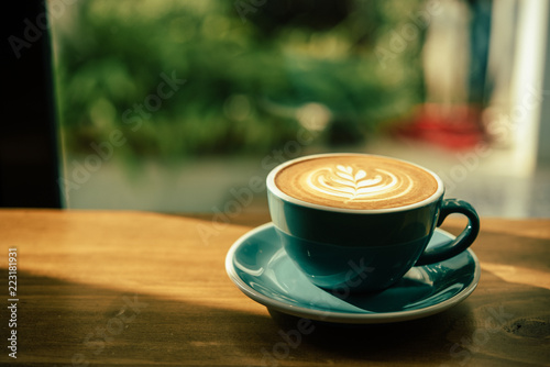 Hot art Latte Coffee in a cup on wooden table and morning light