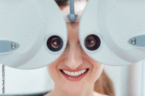 Woman having her eyesight measured with phoropter looking at the camera  photo