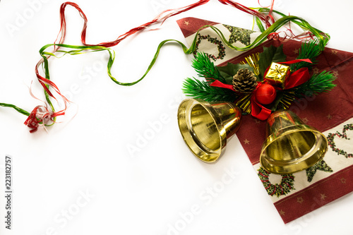 Gold christmas bell on red napkin with branches of fir tree, red ball and yellow gifts isolated on white. Christmas and New year theme and symbols. Winter holidays. Gold, red, green and red colors.