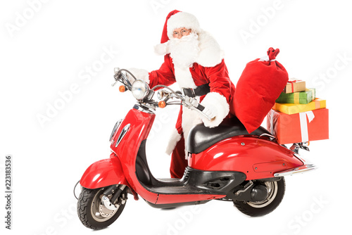 santa claus pushing vintage red scooter with sacks and gift boxes isolated on white
