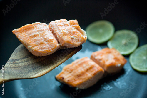 Close up grilled salmon steak on black pan with 3 lemon slices. image for background, wallpaper and copy space.