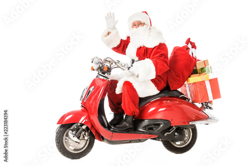 santa claus riding vintage red scooter and waving at camera isolated on white