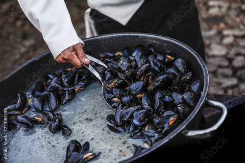 cozze cucinate da un cuoco nella padella photo