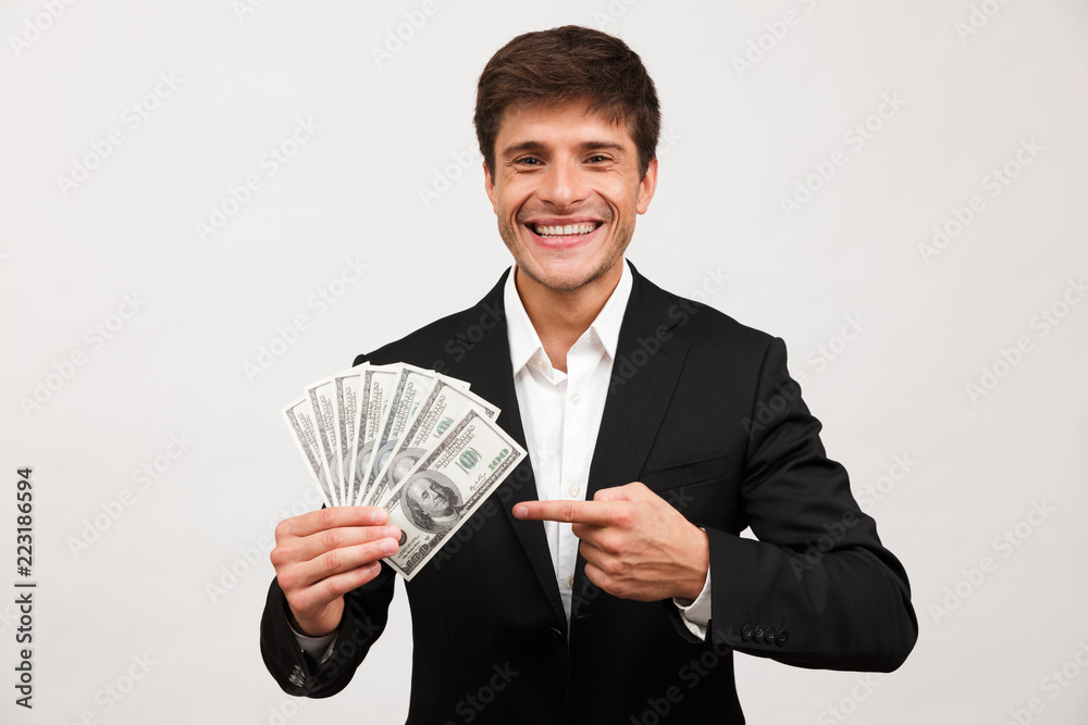 Happy businessman standing isolated holding money pointing. Happy businessman standing isolated holding money pointing.