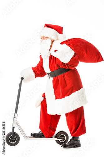 side view of santa claus with sack riding scooter isolated on white