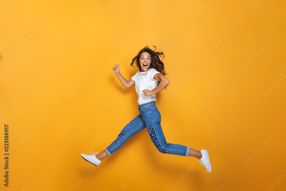 Full length portrait of a happy girl with long dark hair jumping