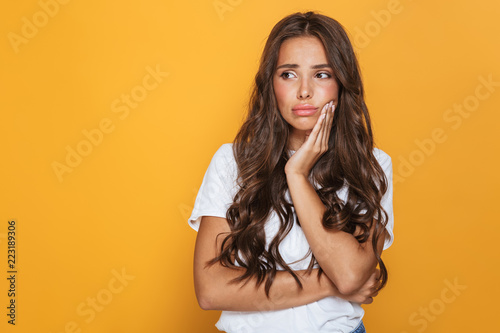 Photo of upset brunette woman in casual clothes looking aside at copyspace  isolated over yellow background