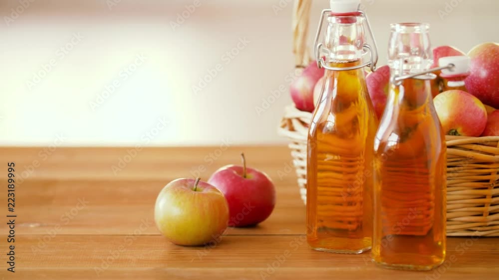 fruits, food and harvest concept - apples in wicker basket and glass bottles of juice on wooden table fruits, food and harvest concept - apples in wicker basket and glass bottles of juice on wooden table