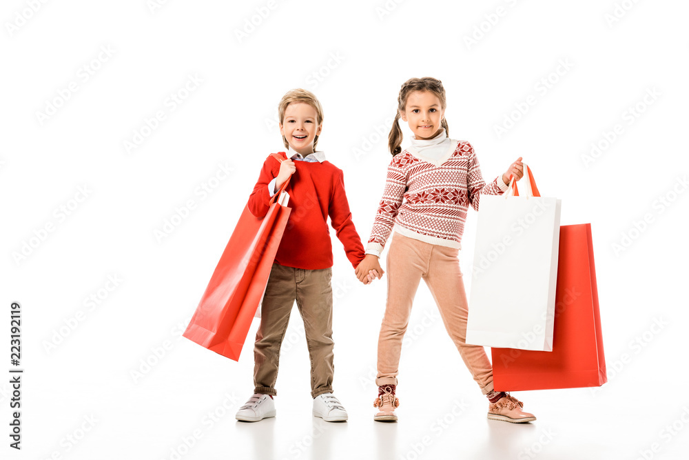 adorable little kids in christmas sweater holding big paper bags isolated on white