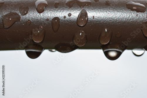 Rain drops on a brown pipe outside on a stormy day photo