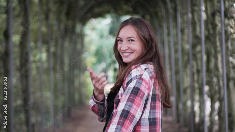 Woman in plaid shirt in autumn park. close-up, smile. A woman calls for herself and runs off into the distance. The shirt develops in the wind Woman in plaid shirt in autumn park. close-up, smile. A woman calls for herself and runs off into the distance. The shirt develops in the wind