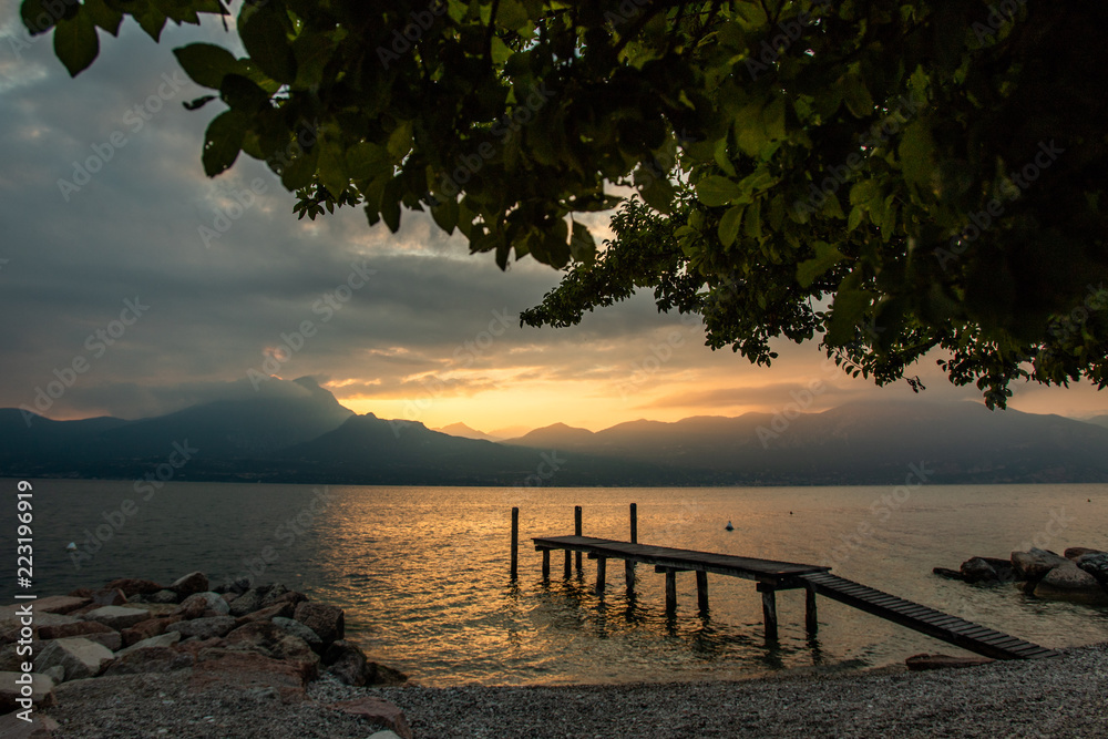 Landscape of Lake Garda, Italy with pier during beautiful summer sunset