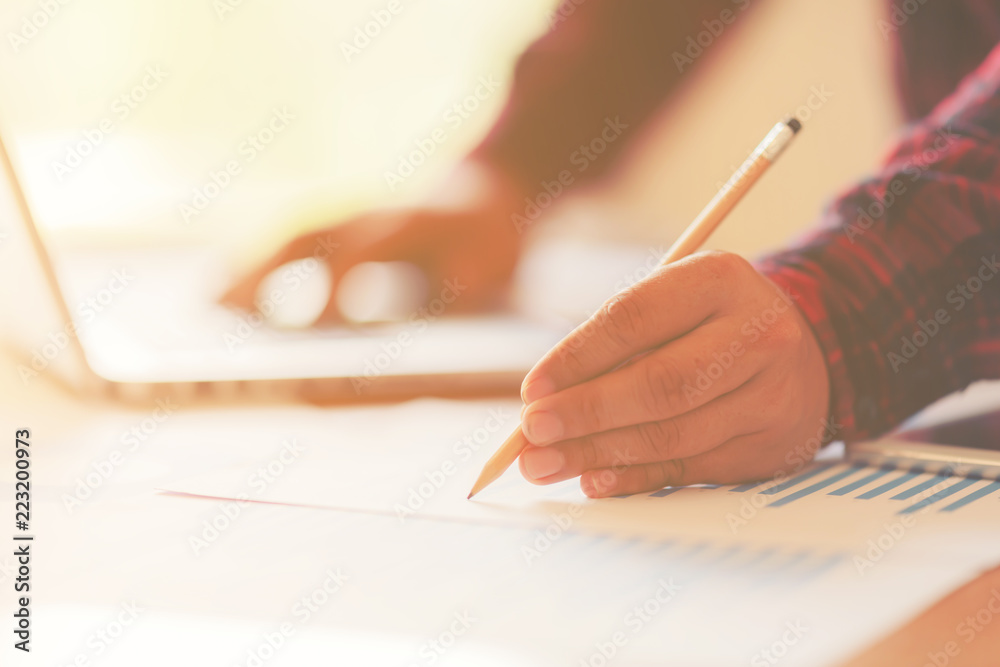 Working process startup. Businessman working at the wood table with new finance project. Modern notebook on table. Pen holding hand Working process startup. Businessman working at the wood table with new finance project. Modern notebook on table. Pen holding hand