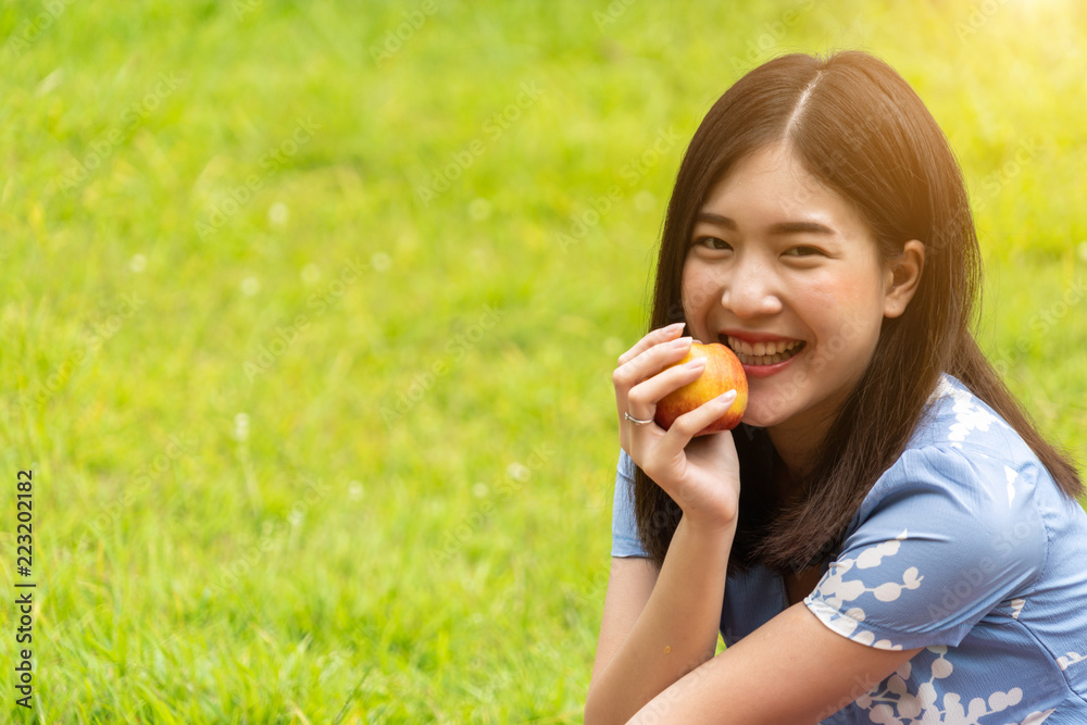 Portrait of girl eat an apple sitting on grass field Portrait of girl eat an apple sitting on grass field